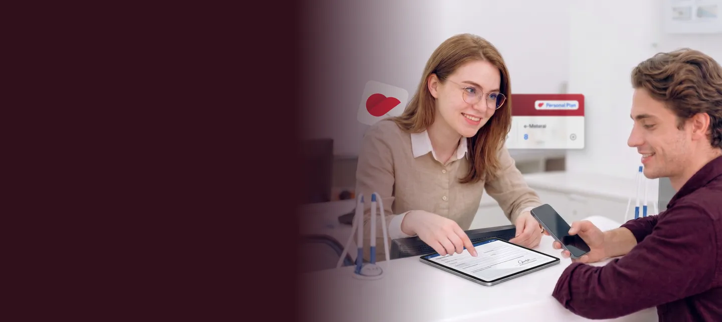 A woman guiding a smiling man through signing on a tablet at a service desk